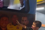 梅西坐在大巴后排位置与被举起来的小朋友打招呼